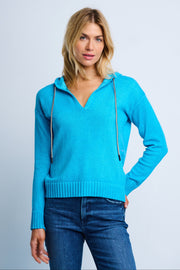 Woman wearing a blue hoodie and jeans against a light gray background