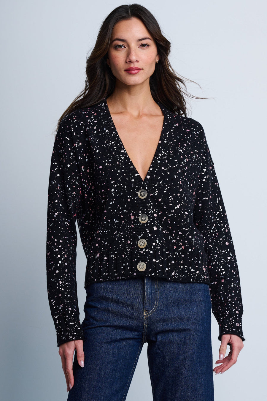A woman modeling a black cotton cardigan with a metallic print, featuring drop shoulder sleeves and a four-button closure.