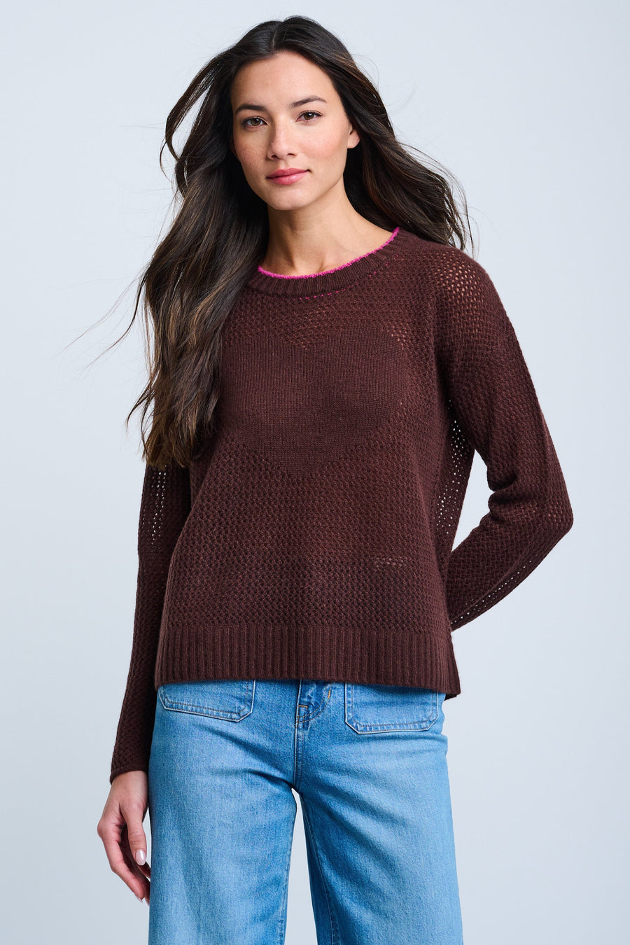 A woman wearing a long sleeve, maroon sweater with a round neckline. The sweater has a relaxed fit and the model has long, dark hair.