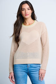 A woman wearing a beige open front cashmere sweater with heart intarsia and contrast tipping at the neckline, paired with blue jeans.