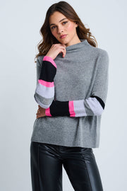 A female model wearing a gray mock neck pullover with contrast color block sleeves and ribbed finishing at cuffs and bottom hem.