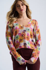 Woman wearing a colorful floral-patterned sweater against a plain background