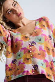 Woman wearing a colorful floral-patterned sweater against a plain background