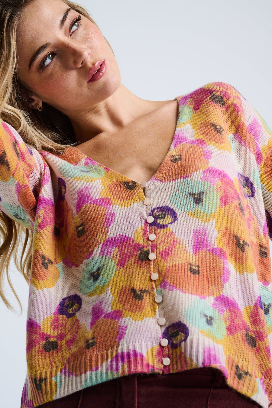 Woman wearing a colorful floral-patterned sweater against a plain background