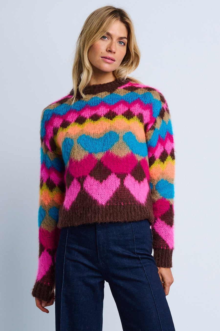A woman modeling a multicolored geometric patterned crew neck sweater