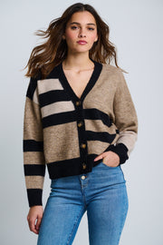 A female model wearing an oversized fit colorblocked cardigan with a v-neck and four-button closure, paired with blue jeans.