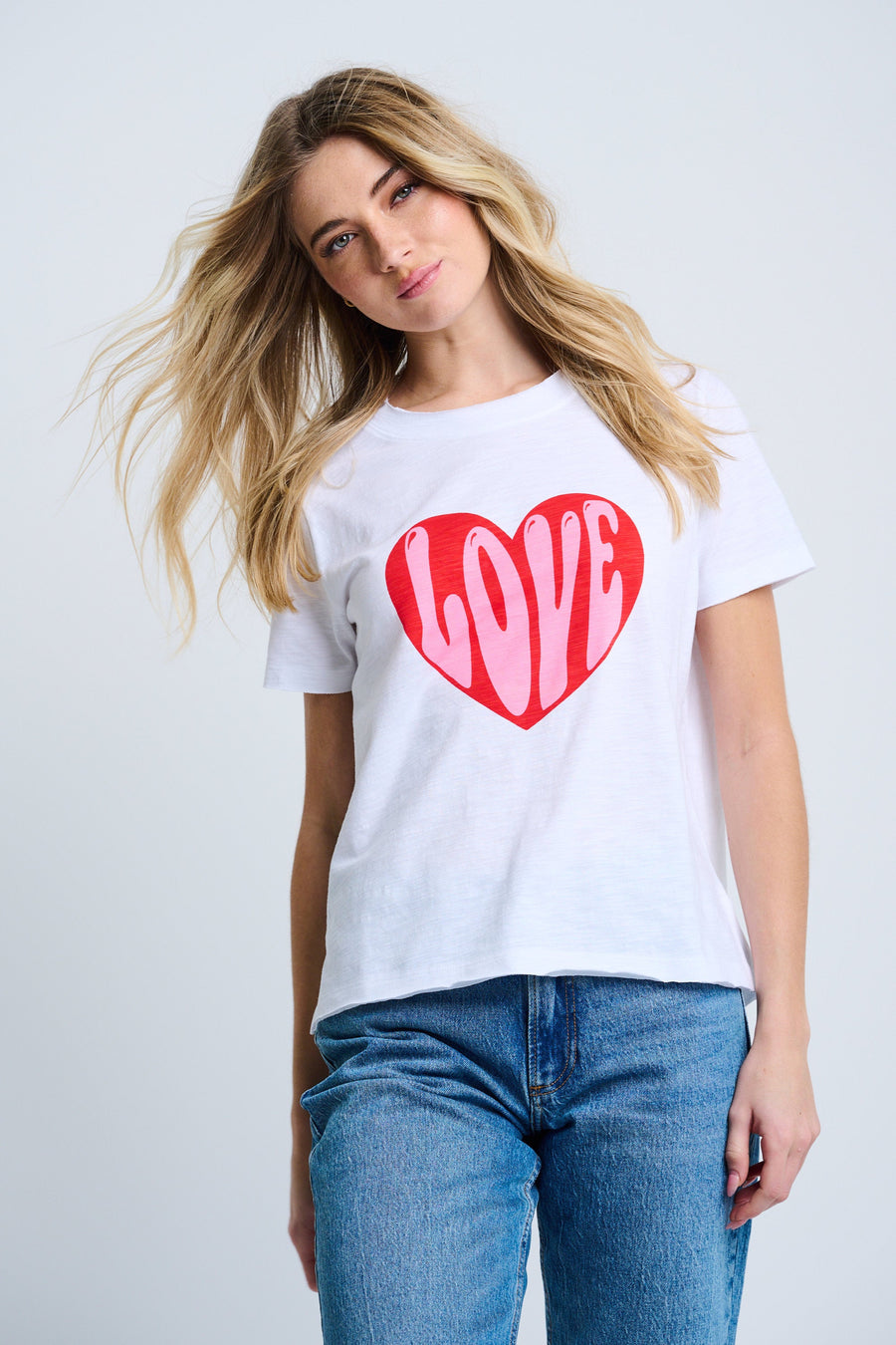 Woman wearing a white t-shirt with a red heart and 'LOVE' text on a plain background