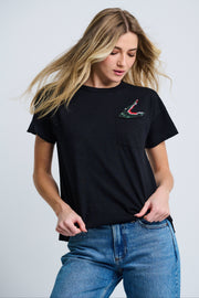 A female model wearing a black short-sleeve crew t-shirt with an embroidered alligator applique above the chest pocket, paired with blue jeans.