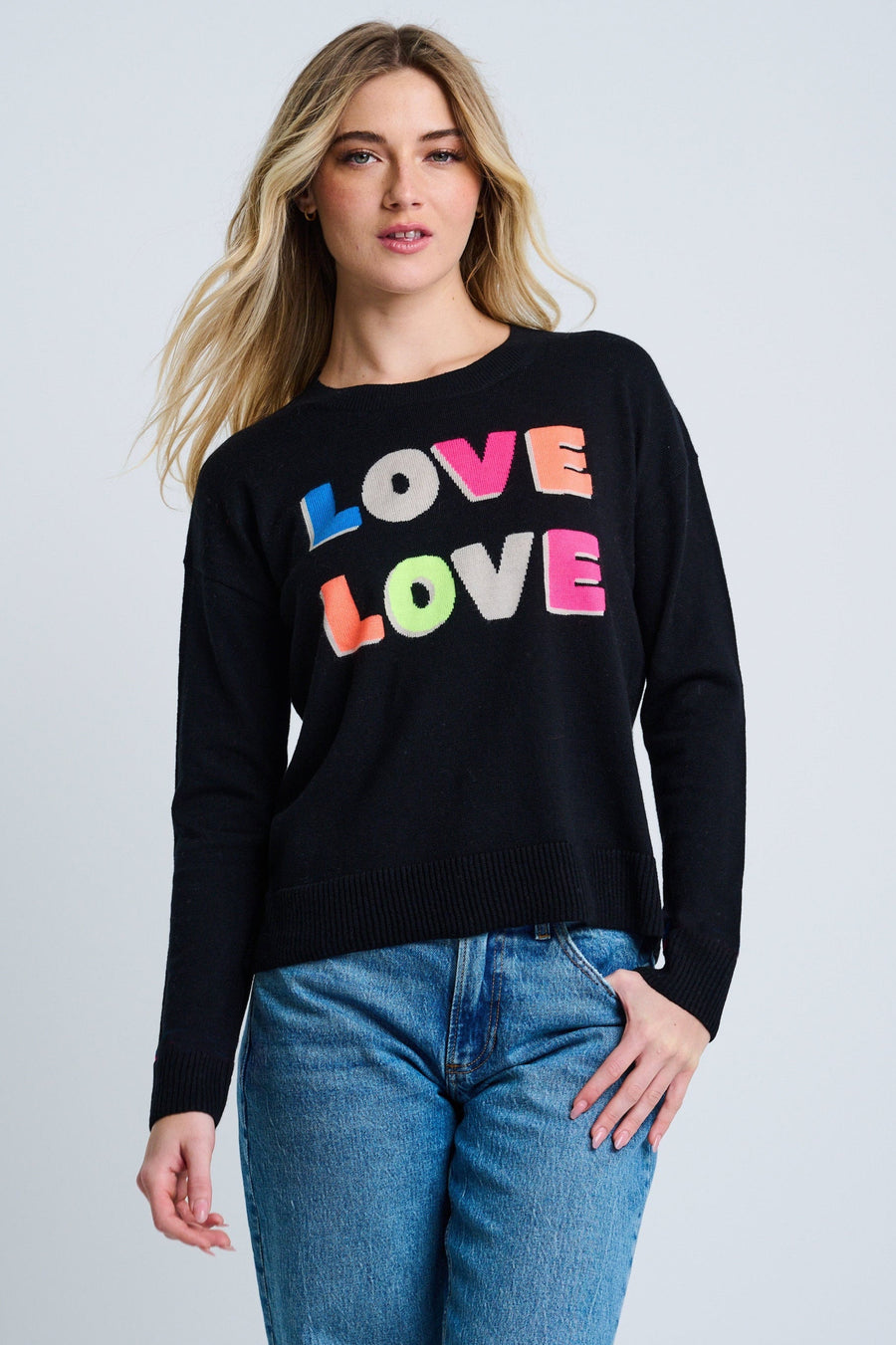 Woman wearing a black sweater with 'LOVE' in colorful letters on a plain background