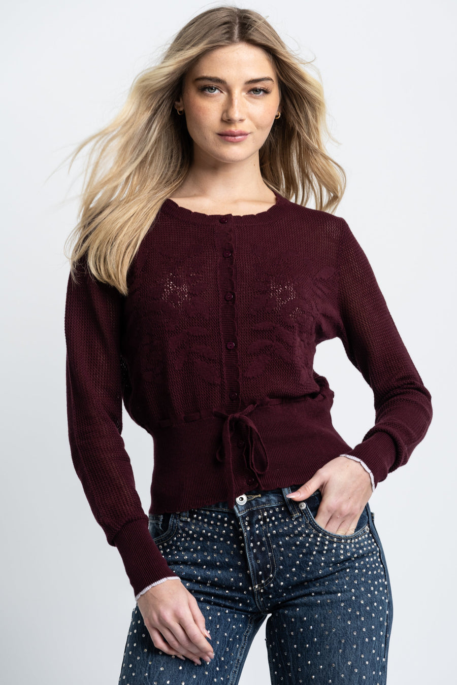 Woman wearing a burgundy sweater and polka dot jeans on a white background