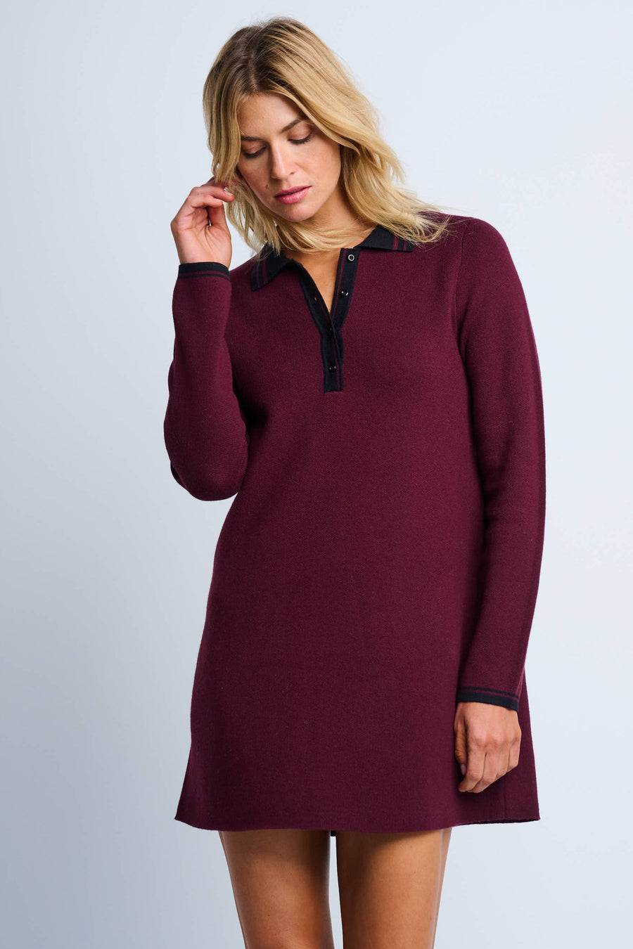 A woman modeling a long-sleeve maroon A-line dress with a contrast button-up collar and striped cuffs.
