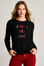 Woman wearing a black sweater with colorful text on a plain background