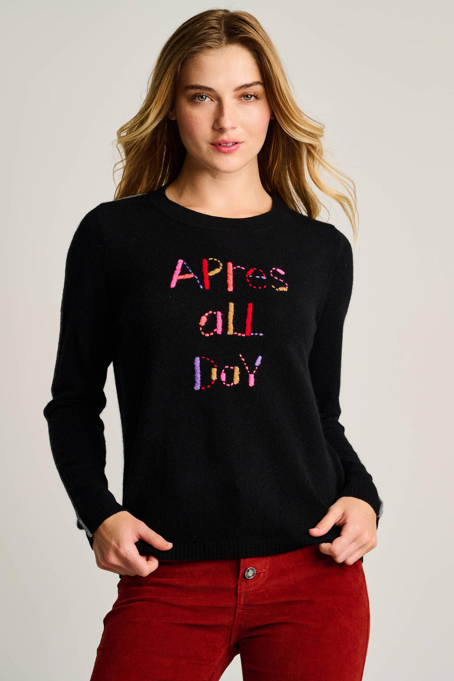 Woman wearing a black sweater with colorful text on a plain background