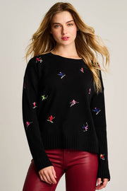Woman wearing a black sweater with colorful embroidered designs on a plain background
