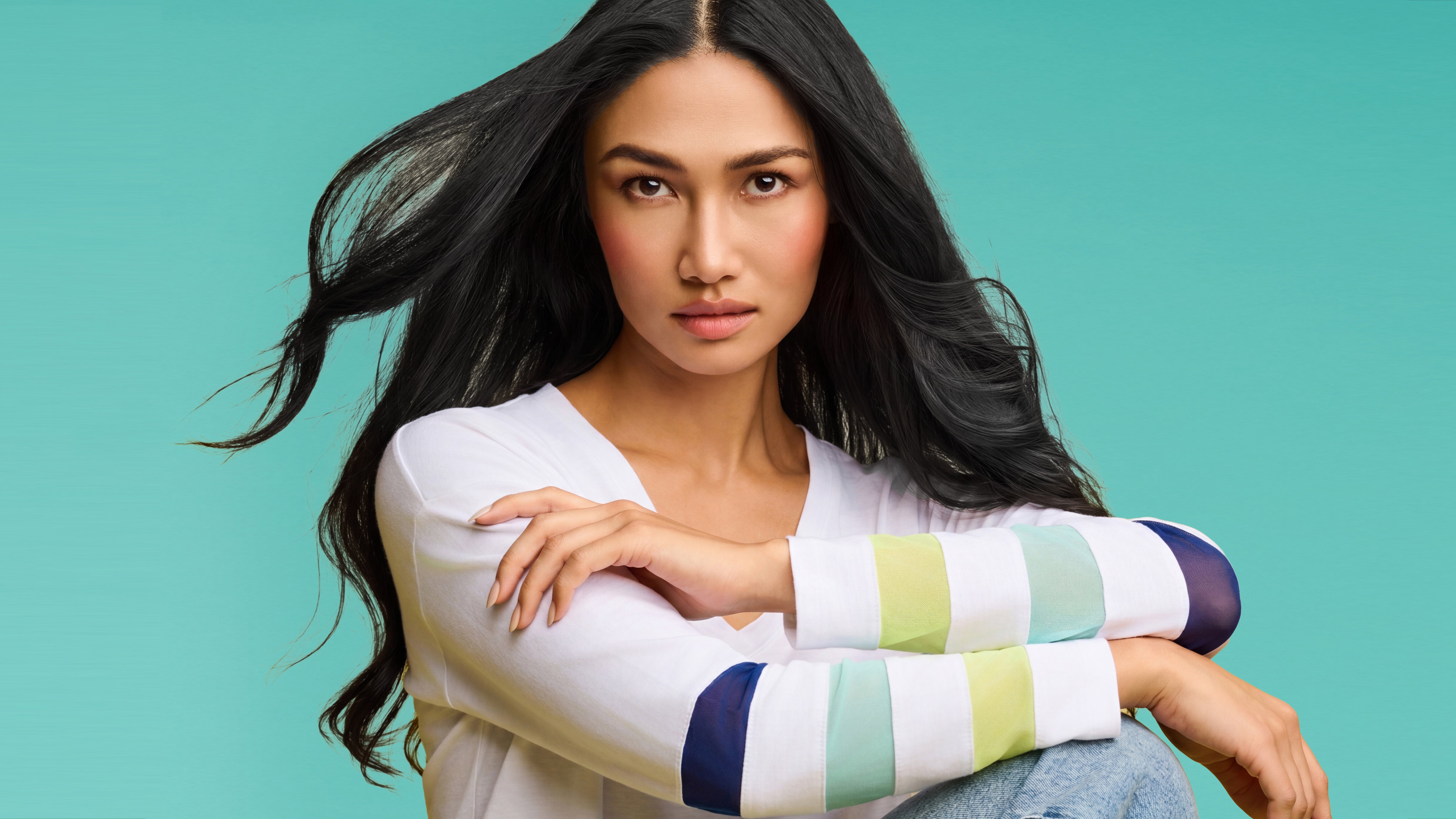 Woman wearing a colorful striped sweater against a teal background